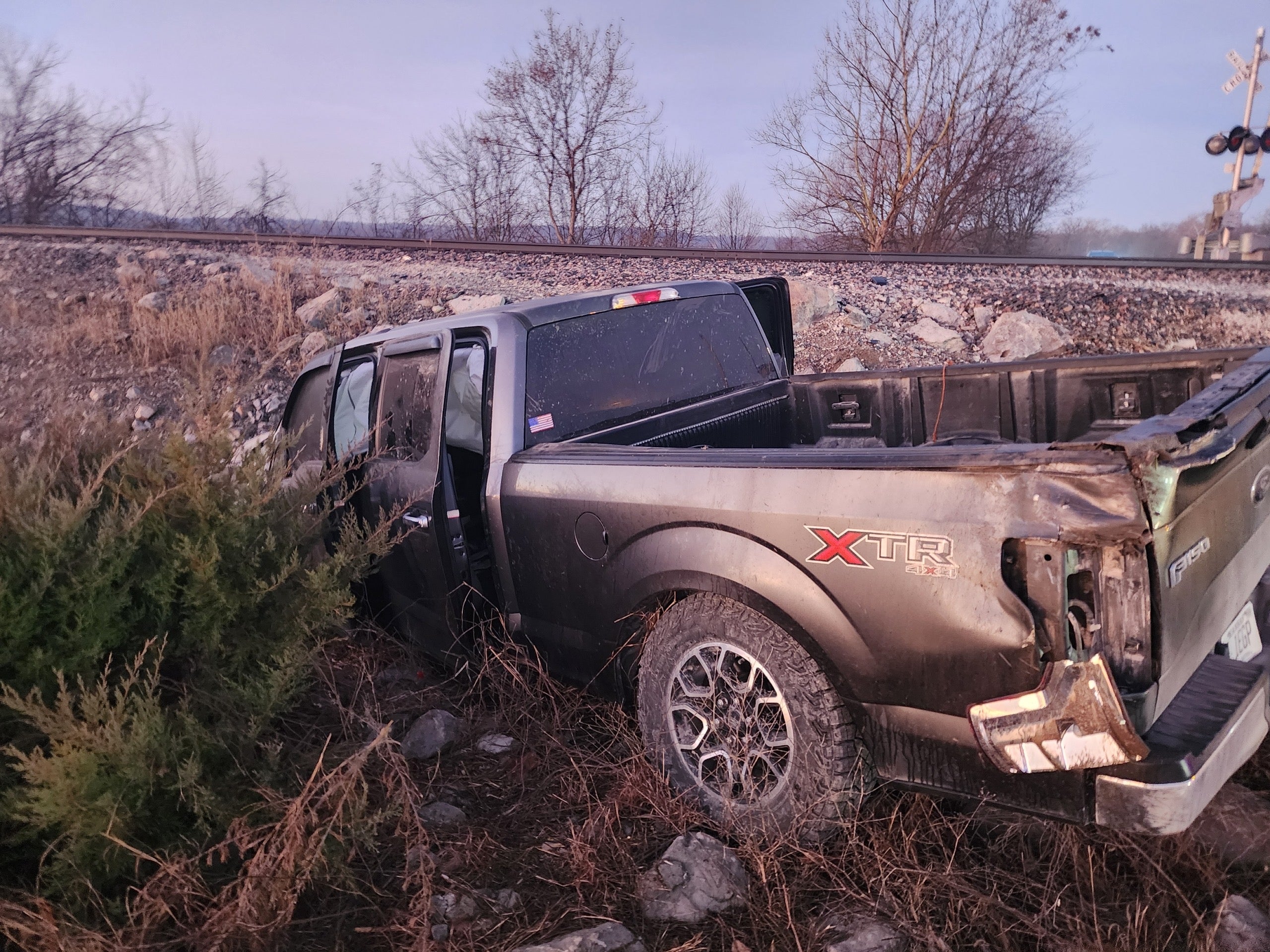 Gray Ford F-150 in a ditch on the side of a road after a wreck