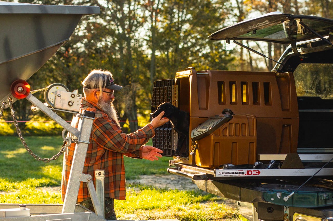 Jeff Coats pets a Black Labrador Retriever who is standing in the back on a G1™ Kennel in Susquehanna brown in the back of a pickup truck.