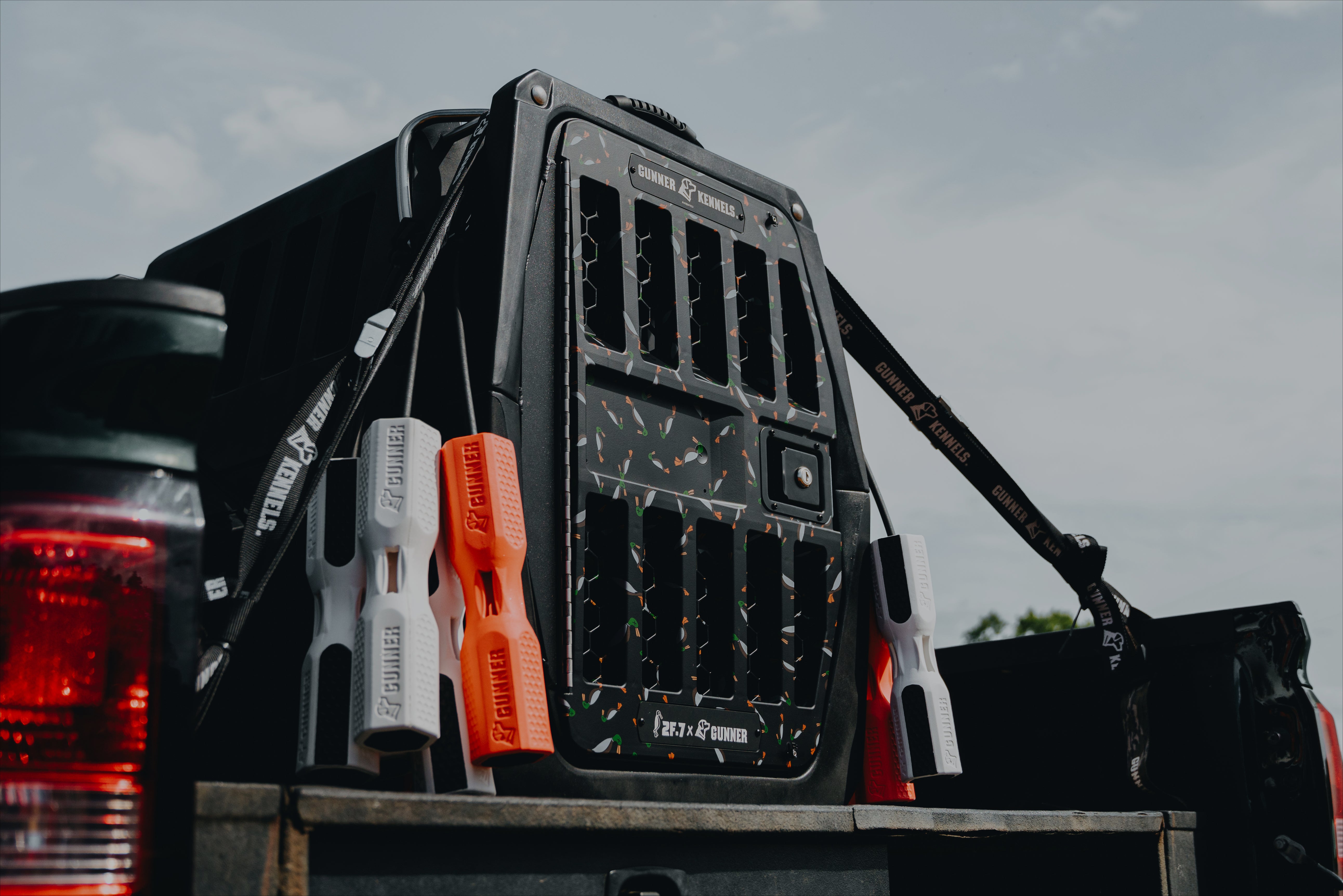 A black gear organizer with attached screwdrivers is mounted on the back of a truck under a partly cloudy sky.