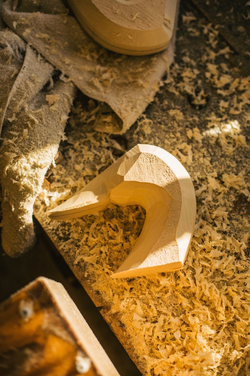 A duck head carving lays on a table covered in wood shavings.