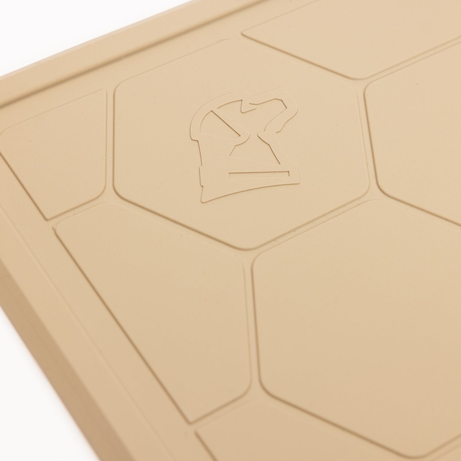 Close-up of the GUNNER BOWL MAT - TAN, featuring a slip-resistant hexagonal pattern and a raised knight chess piece symbol in the corner.