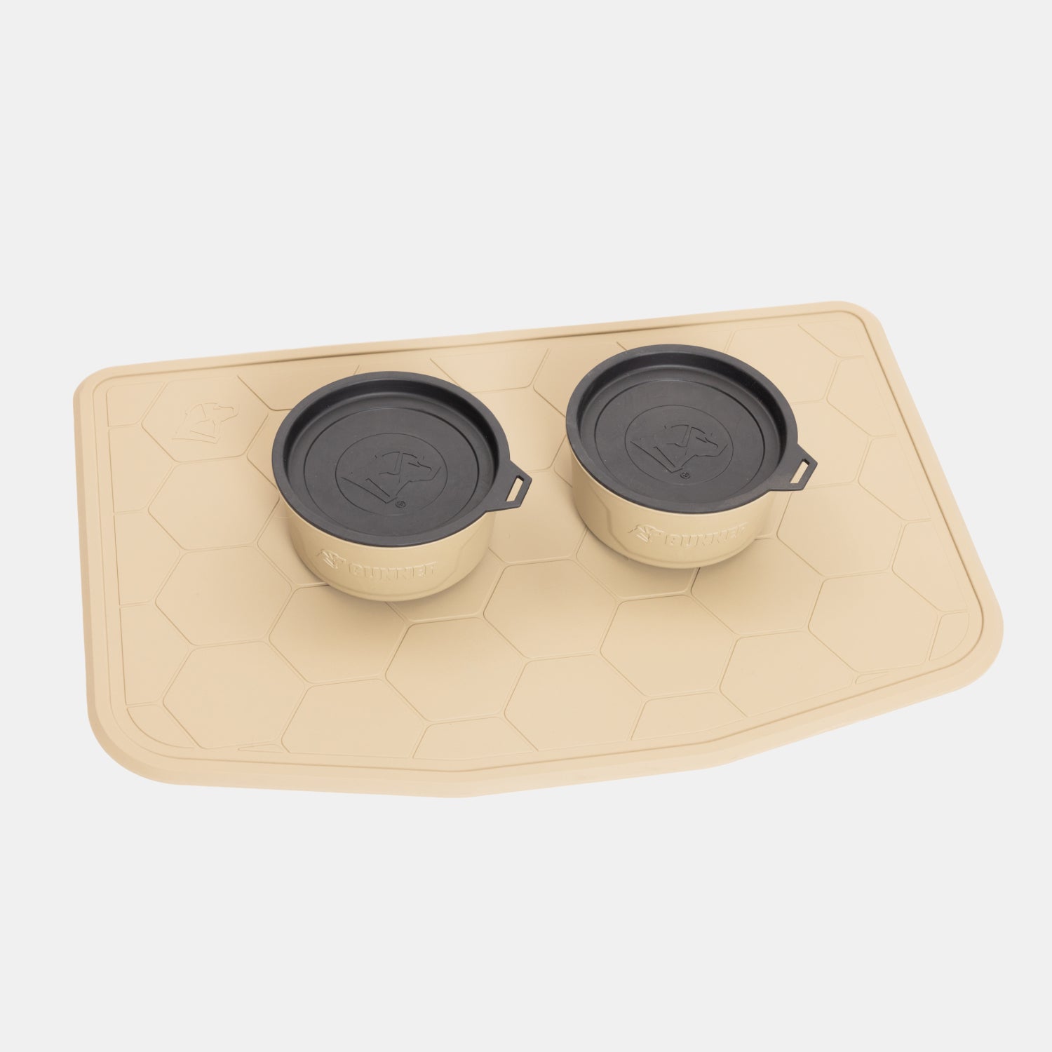 The GUNNER Feed Bundle features two tan dog bowls with black lids arranged on a coordinating tan, hexagon-patterned bowl mat, providing a stylish and practical feeding setup against a white backdrop.