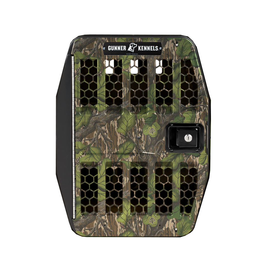 A camouflage-patterned dog crate with black hexagonal ventilation slots and a lockable door on the right, branded with Gunner Kennels at the top—perfect outdoor gear for your adventurous pup.