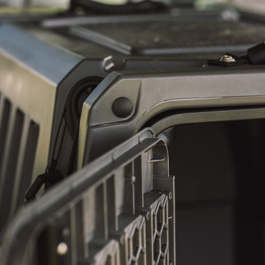 Close-up of the GUNNER G1™ KENNEL - FLINT shows its sturdy plastic build, door hinge, and textured surface. Designed for durability, this crate is secure and reliable—ideal for safe animal transport.