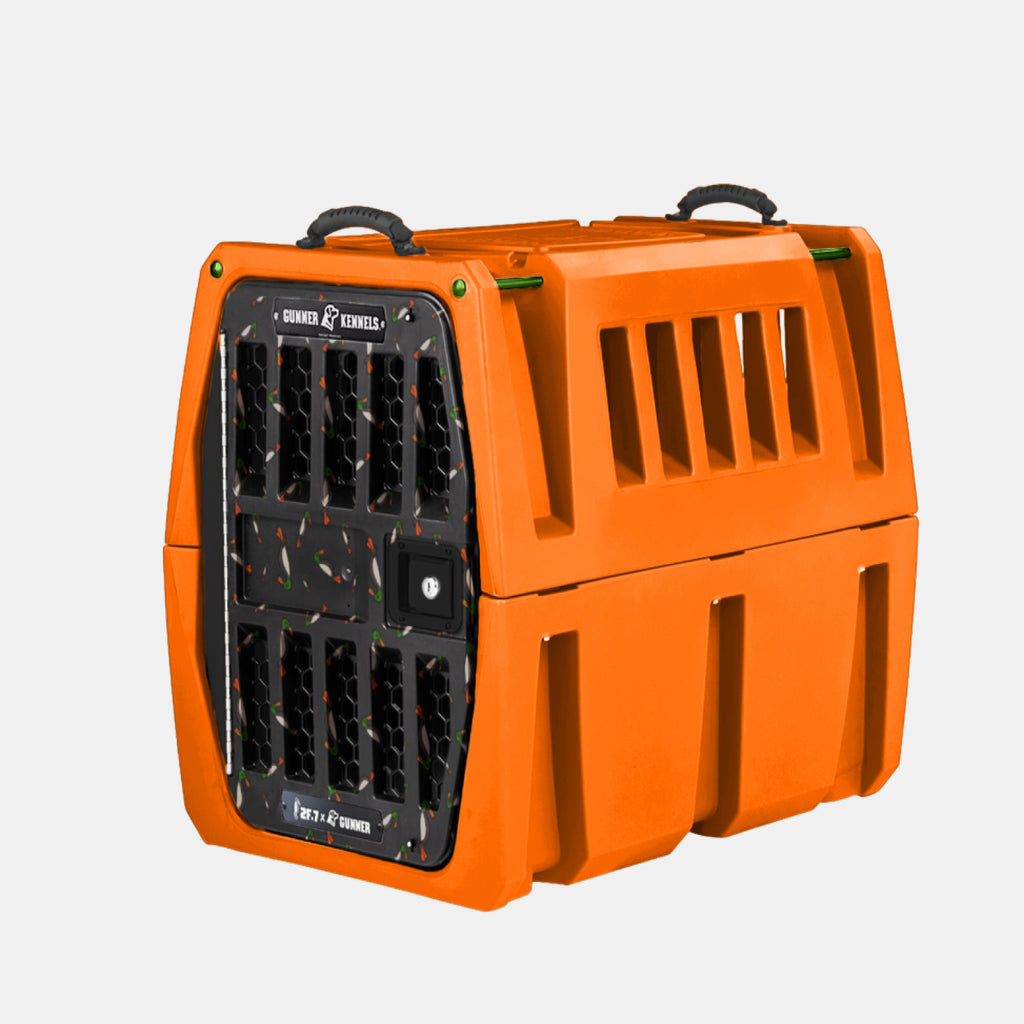 The GUNNER G1™ KENNEL - 2F.7 ORANGE CRUSH is a sturdy, double-walled orange crate with side ventilation slats and a secure grated black door, offering shock protection for safe and reliable dog transport.