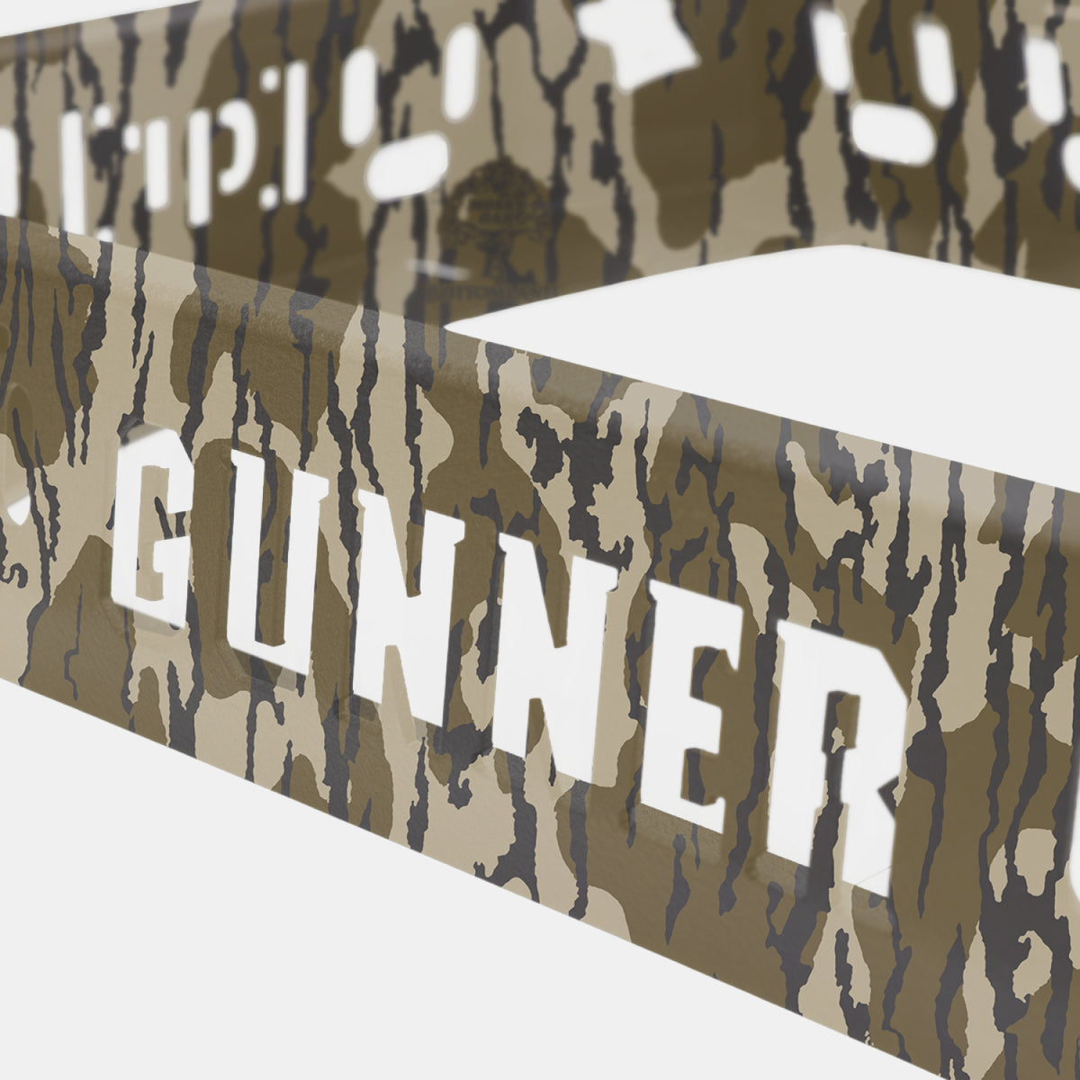Close-up of a camouflage-patterned metal frame featuring the word GUNNER cut out in bold letters. Shown here is the Kennel Rack - Mossy Oak Bottomland by GUNNER—a heavy-duty storage system engineered to maximize your truck bed space. The crisp white background accentuates both its distinctive design and practical branding.