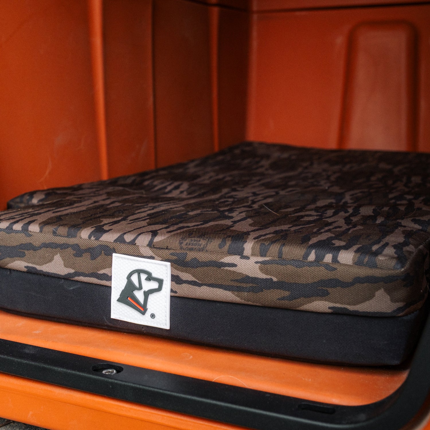 The GUNNER LONG HAUL BED, featuring a camouflage pattern and a dog head logo, is shown inside an orange crate.