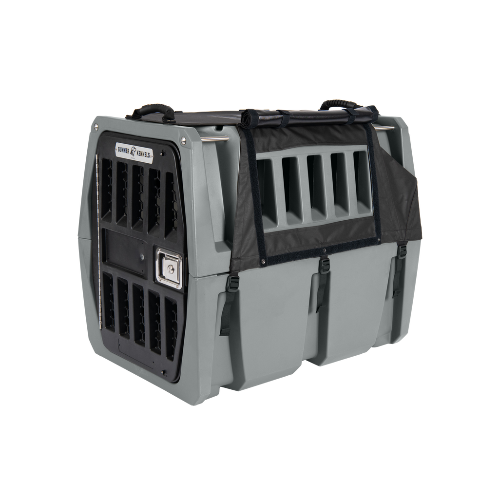 A sturdy gray plastic dog crate with ventilation slats, a secure latch door, carrying handles on top, and a black fabric cover partially attached—ideal for hunting dogs or as reliable outdoor gear.