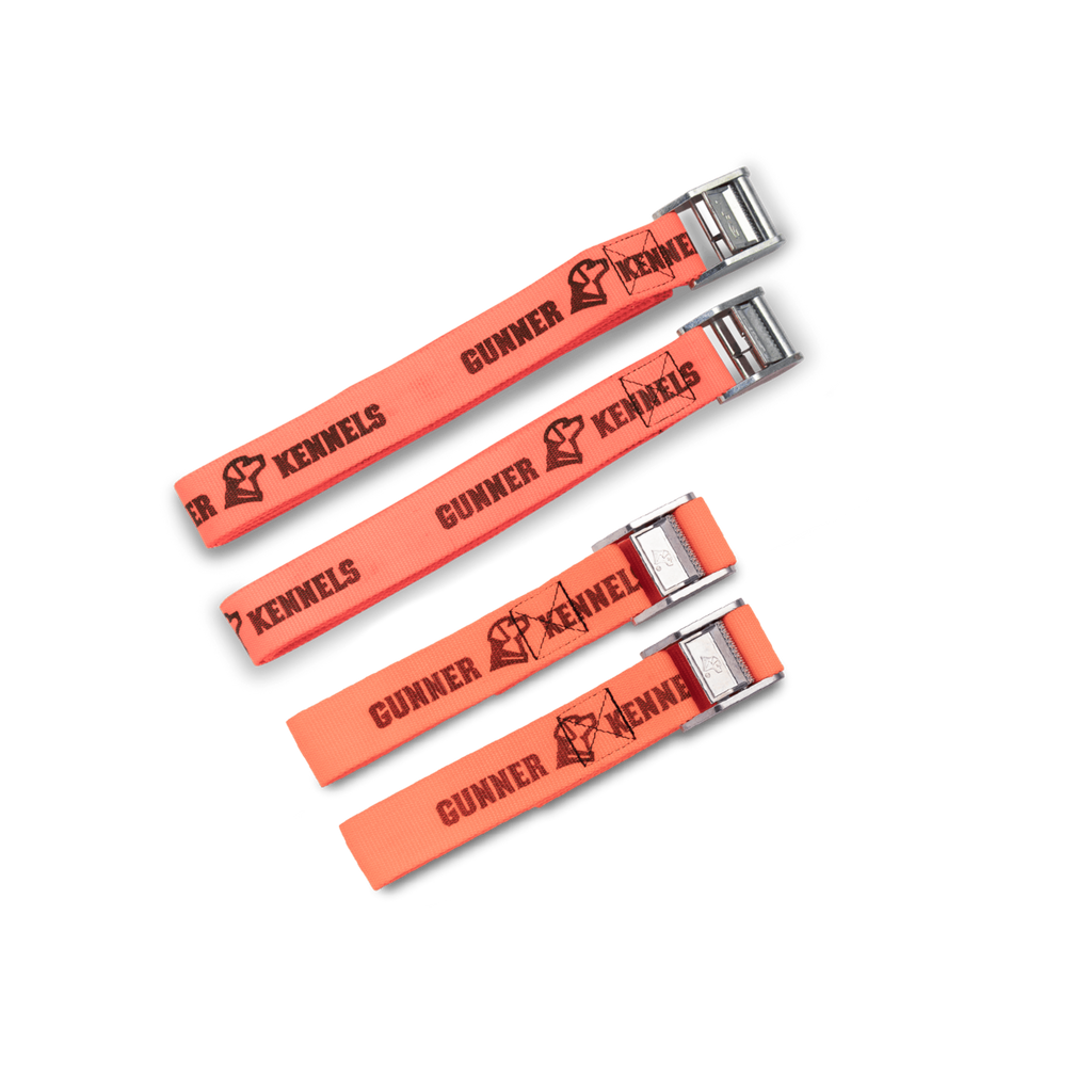 Four orange TIE-DOWN STRAP KITs by GUNNER, featuring black GUNNER text and dog head logo, are displayed in descending size order on a white background. Each has a silver buckle and is inspired by our crash-tested dog crate.