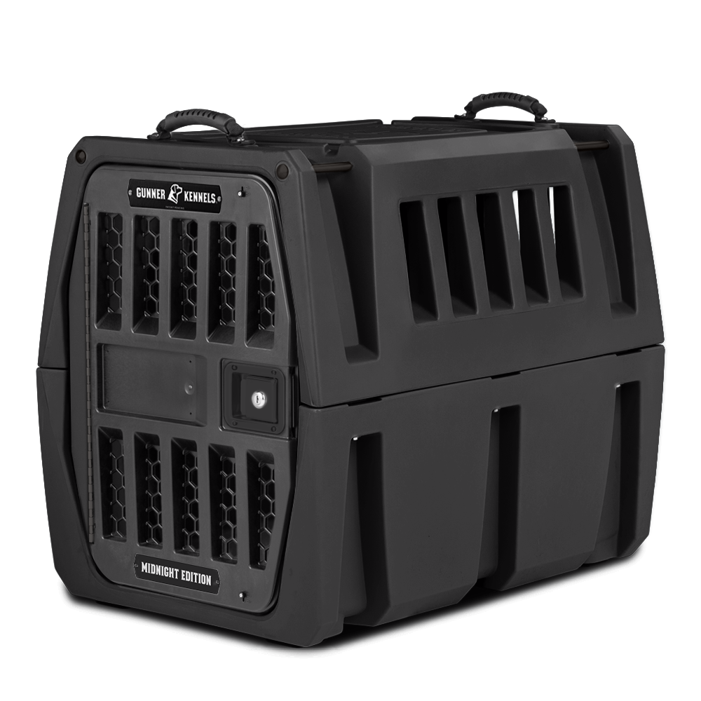 A sturdy, black plastic dog crate labeled Gunner Kennels Midnight Edition with ventilation slats on the sides and front, secure latches, and top handles—perfect outdoor gear for carrying your working dog safely and securely.